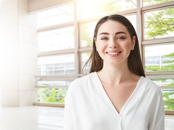 Eine lachende Frau vor einem Fenster.