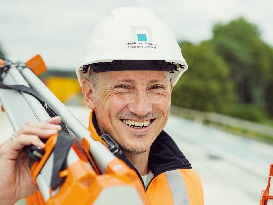 Ein lachender Mann in Sicherheitskleidung.