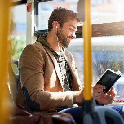 Ein Mann sitzt im Bus und liest ein Buch.