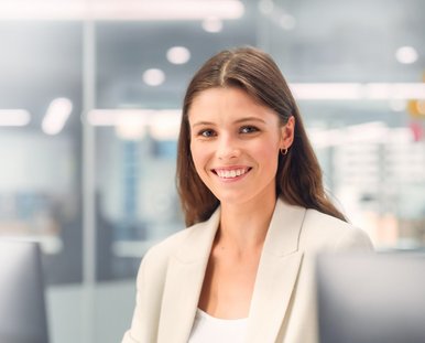 Eine lachende Frau sitzt vor einem Computer.