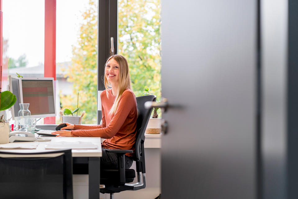 Eine lachende Frau sitzt am Schreibtisch